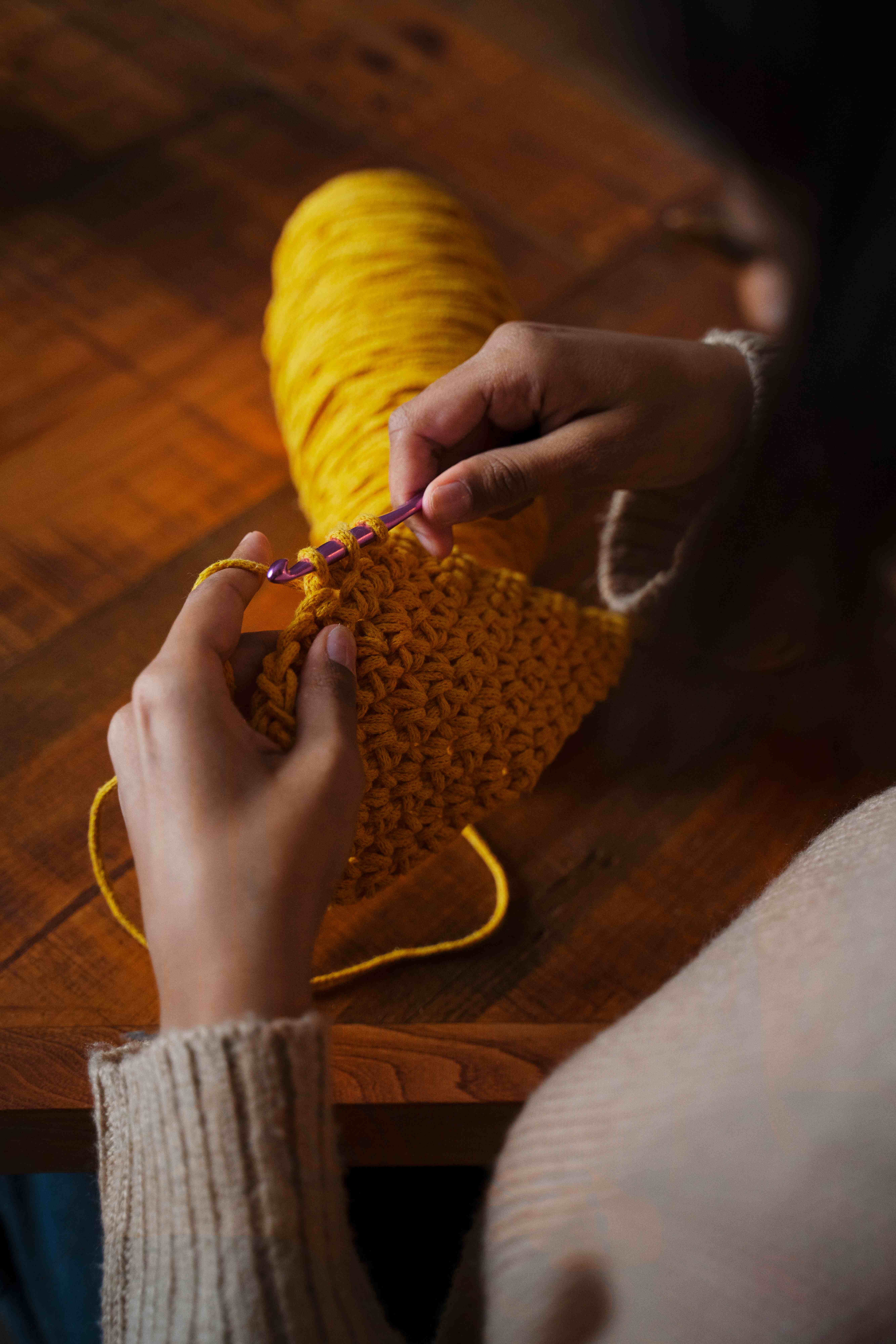 Artista tejiendo con lana amarilla